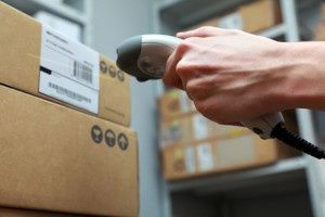 A man gets on the hip scaner in operations directed on printed barcode. Warehouse scene. Shallow DOF!